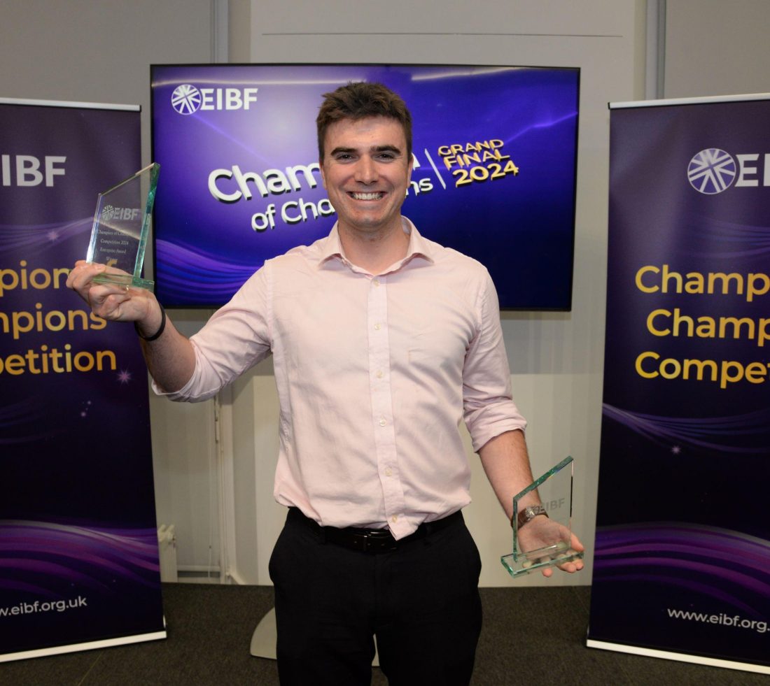 Student smiling holding two glass awards