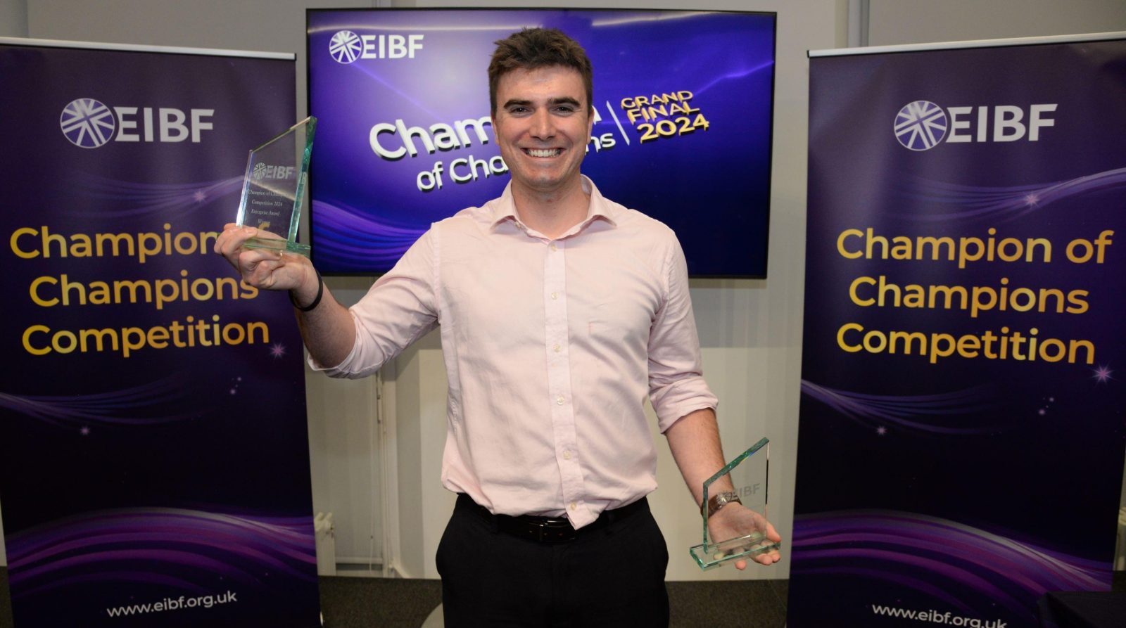 Student smiling holding two glass awards