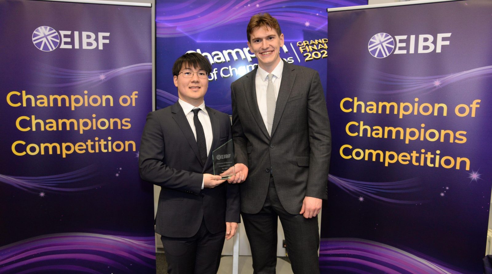 Two students smiling holding glass award