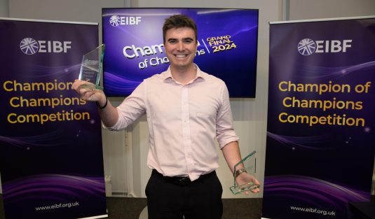 Student smiling holding two glass awards
