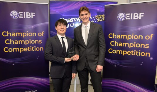 Two students smiling holding glass award