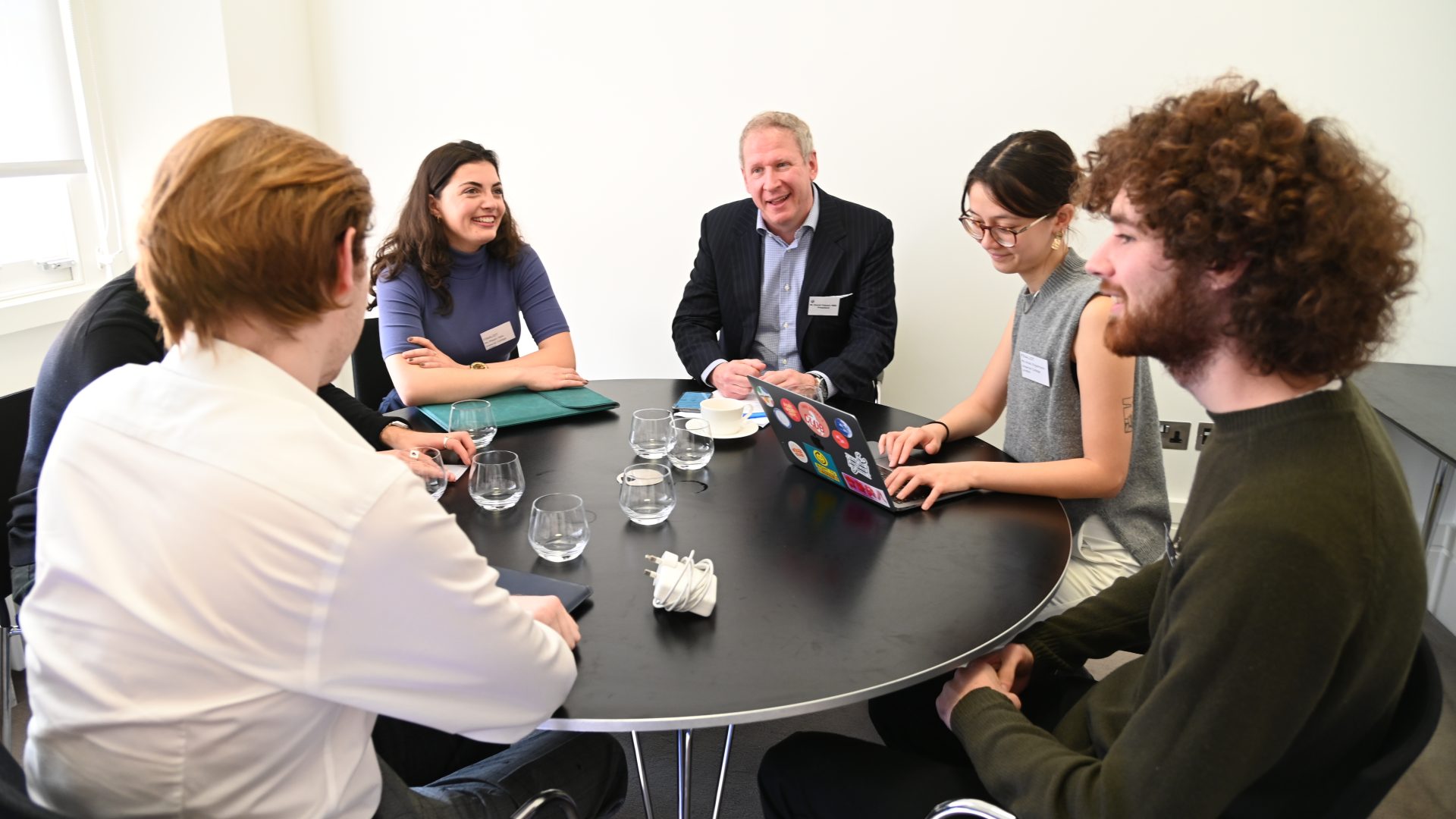 Group of people smiling sitting around a table chatting