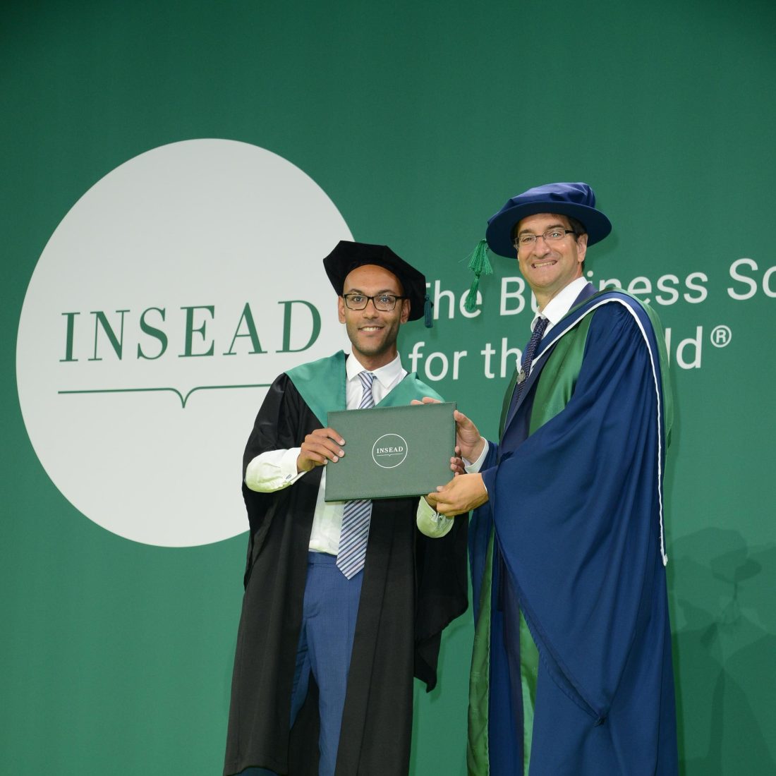 A graduate being presented an award by another academic